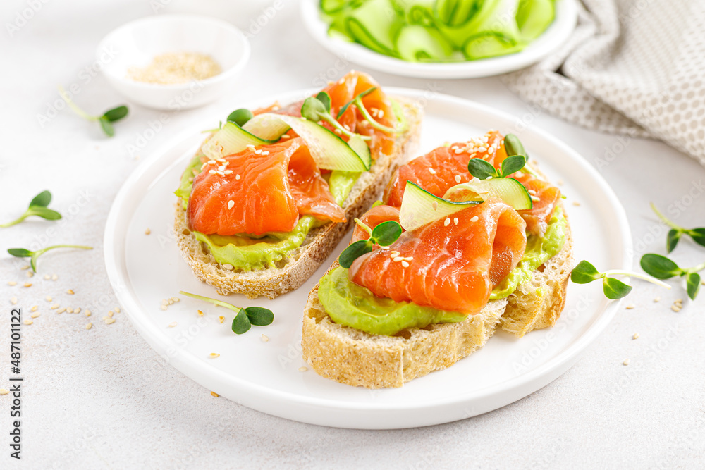 Open sandwiches with salted salmon, guacamole avocado and microgreens. Seafood. Healthy food.