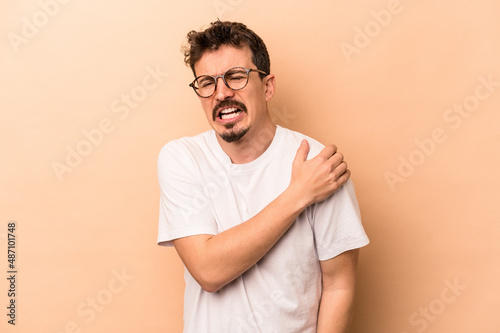 Young caucasian man isolated on beige background having a shoulder pain.