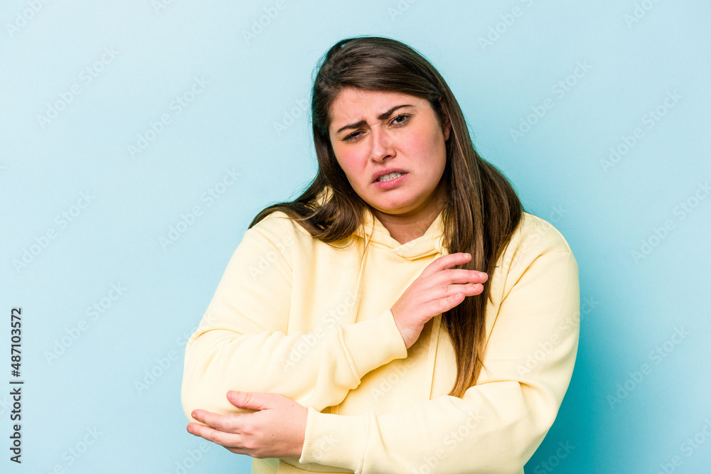 Young caucasian overweight woman isolated on blue background massaging elbow, suffering after a bad movement. Young caucasian overweight woman isolated on blue background massaging elbow, suffering after a bad movement.
