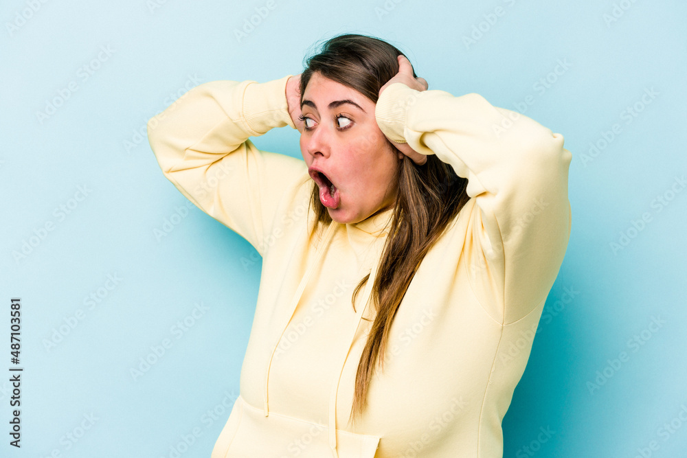 Young caucasian overweight woman isolated on blue background screaming, very excited, passionate, satisfied with something. Young caucasian overweight woman isolated on blue background screaming, very excited, passionate, satisfied with something.