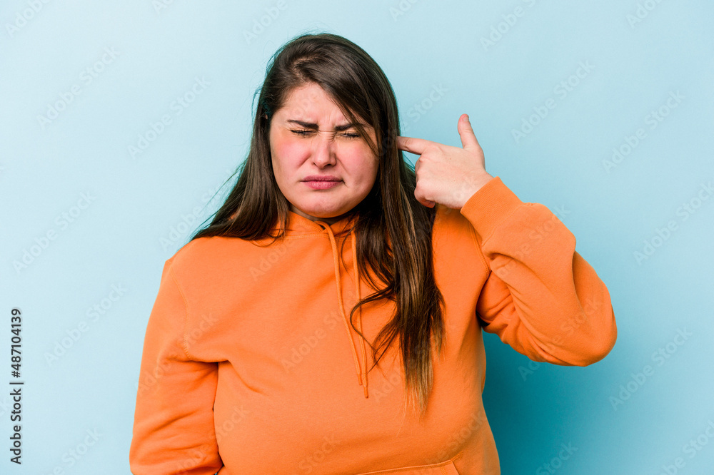 Fototapeta premium Young caucasian overweight woman isolated on blue background covering ears with hands.