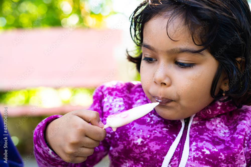 Cute little girl kid busy eating ice cream candy during winter at park ...