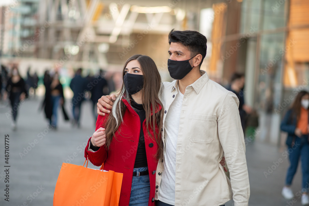 Fototapeta premium Covid and coronavirus shopping, couple walking in a city while carrying shopping bags