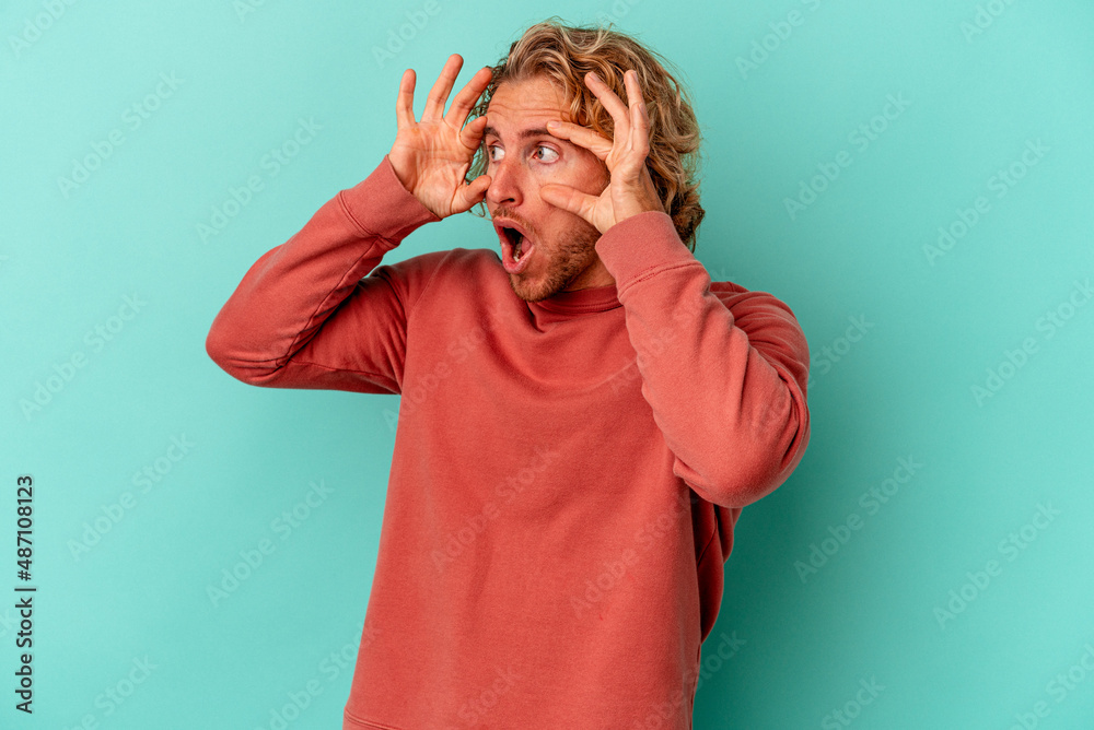 Young caucasian man isolated on blue background keeping eyes opened to find a success opportunity. Young caucasian man isolated on blue background keeping eyes opened to find a success opportunity.