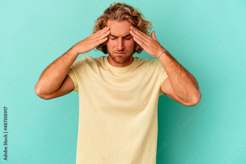 Young caucasian man isolated on blue background having a head ache, touching front of the face. Young caucasian man isolated on blue background having a head ache, touching front of the face.