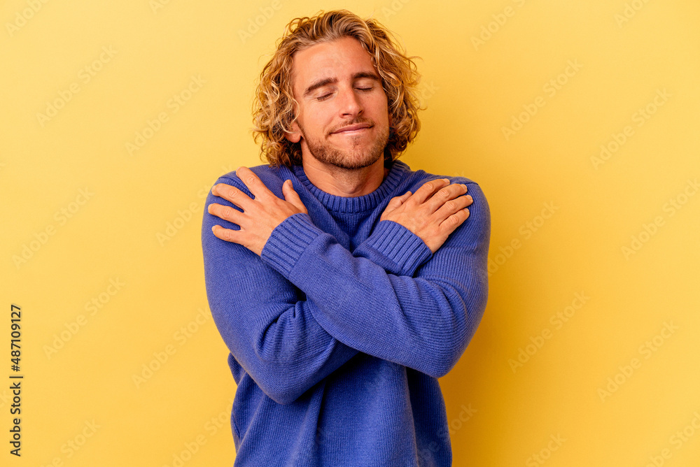 Young caucasian man isolated on yellow background hugs, smiling carefree and happy. Young caucasian man isolated on yellow background hugs, smiling carefree and happy.