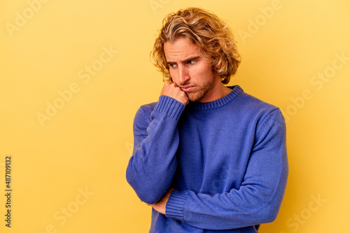 Young caucasian man isolated on yellow background who feels sad and pensive, looking at copy space.