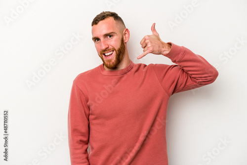 Young caucasian man isolated on white background showing a mobile phone call gesture with fingers.