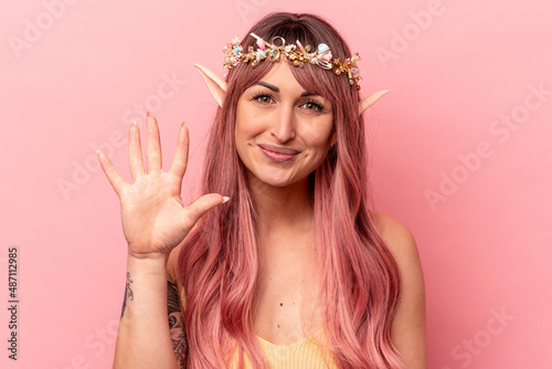 Young caucasian elf woman isolated on pink background smiling cheerful showing number five with fingers.