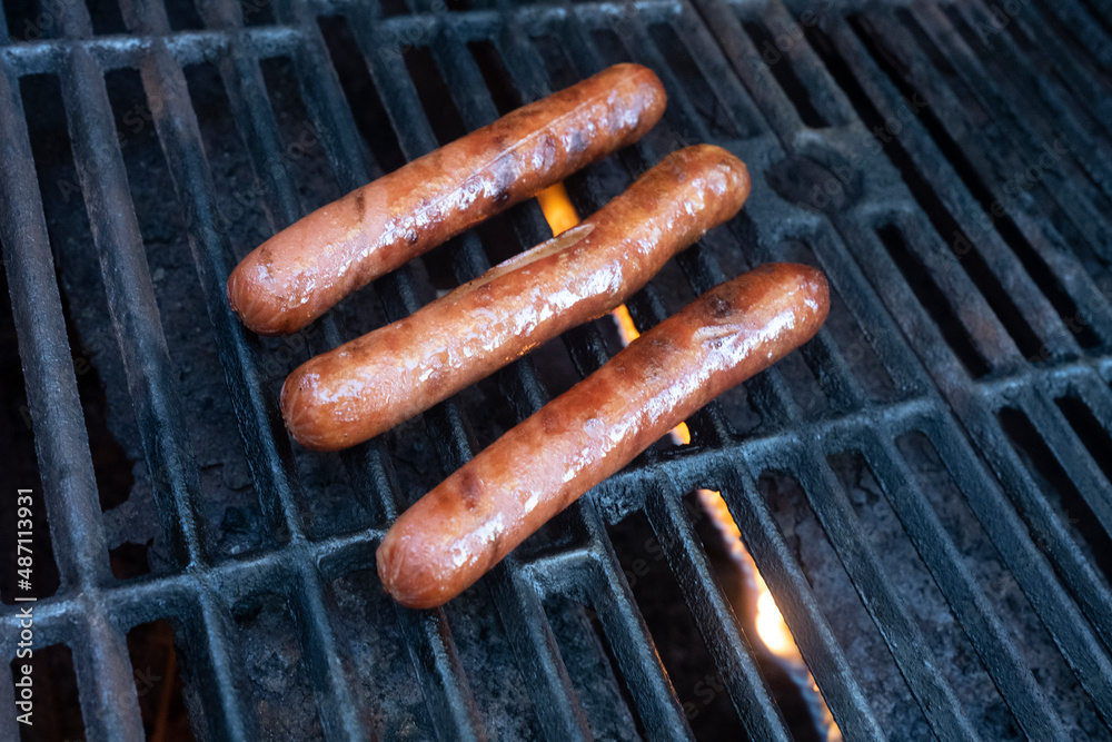Three Hot Dogs Cooking on an Outdoor Gas Grill Three Hot Dogs Cooking on an Outdoor Gas Grill