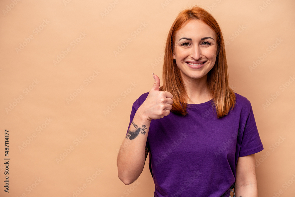 Young caucasian woman isolated on beige background smiling and raising thumb up Young caucasian woman isolated on beige background smiling and raising thumb up