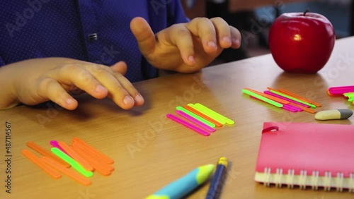 A student at home learns math with counting sticks. A schoolboy at the workplace does his job. Education concept, modern school, knowledge acquisition, traditional learning. UHD 4K.