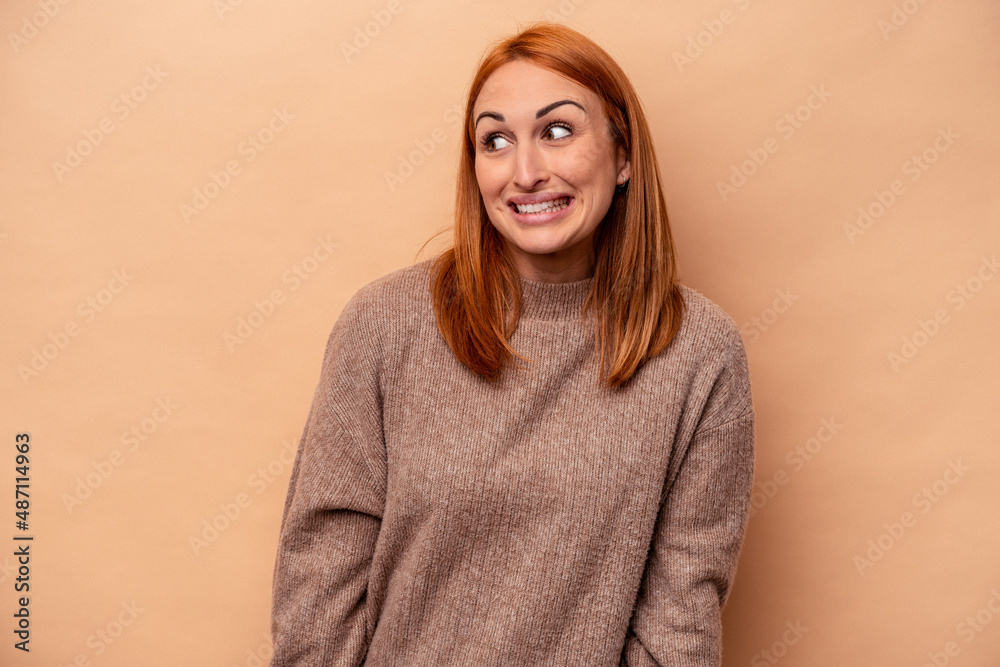 Young caucasian woman isolated on beige background laughs and closes eyes, feels relaxed and happy. Young caucasian woman isolated on beige background laughs and closes eyes, feels relaxed and happy.