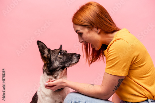 Young caucasian woman with his dog isolated on pink background