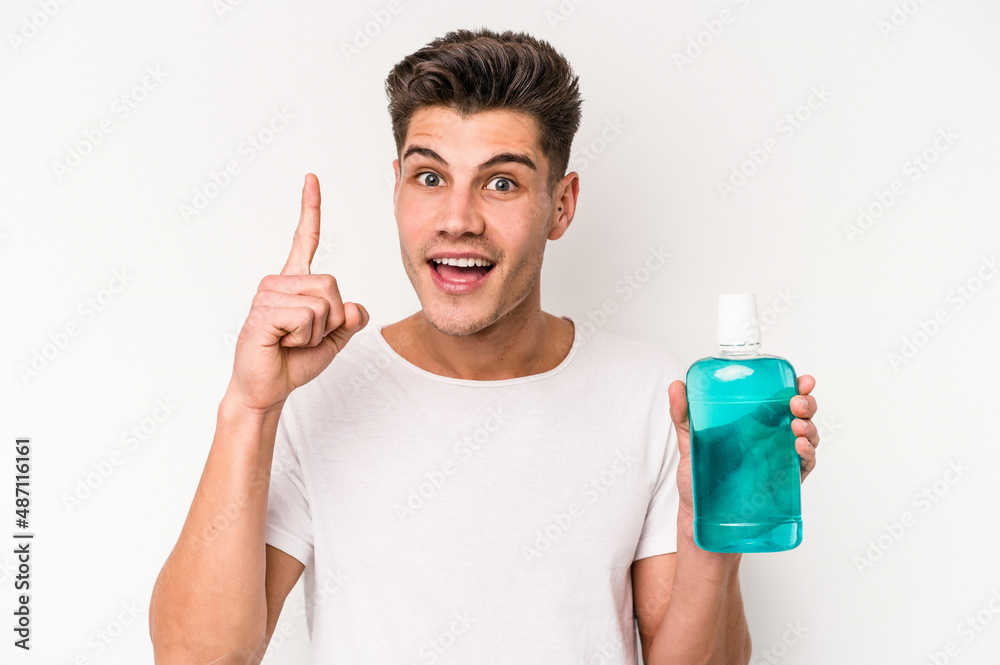 Young caucasian man holding mouthwash isolated on white background having an idea, inspiration concept. Young caucasian man holding mouthwash isolated on white background having an idea, inspiration concept.