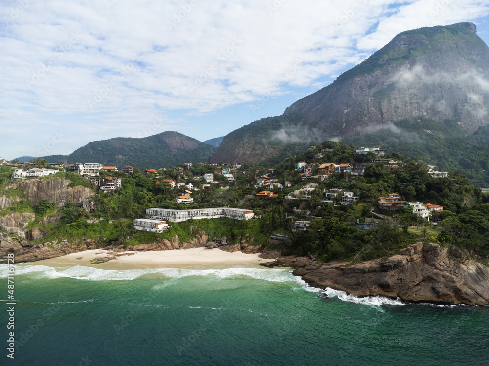 Aerial view of Praia da Joatinga, a paradise in Rio de Janeiro, Brazil with Pedra da Gávea in the background. Sunny day with some clouds in the morning. Sea with good waves for surfers. Drone photo