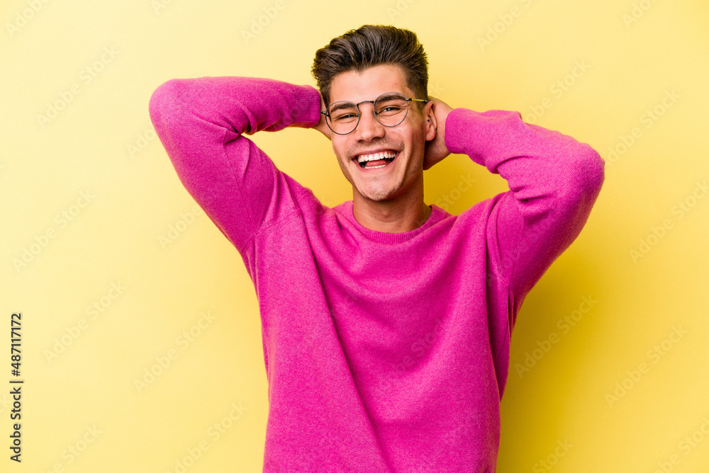 Young caucasian man isolated on yellow background stretching arms, relaxed position. Young caucasian man isolated on yellow background stretching arms, relaxed position.