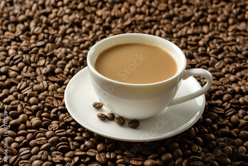 a cup of coffee with milk close-up on the background of coffee beans.