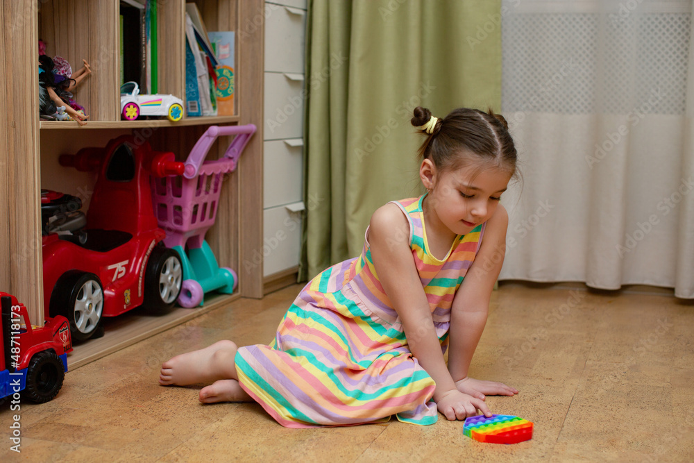 girls are playing pop it in their room on the floor. a game with pop it. colorful antistress sensory toy fidget push pop it in kid's hands girls are playing pop it in their room on the floor. a game with pop it. colorful antistress sensory toy fidget push pop it in kid's hands