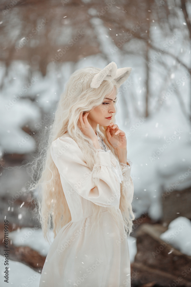 A fabulous white fox girl stands in profile against the background of a winter river. Kitsune on the background of winter nature. Cat girl with white hair on a winter background. A fabulous white fox girl stands in profile against the background of a winter river. Kitsune on the background of winter nature. Cat girl with white hair on a winter background.