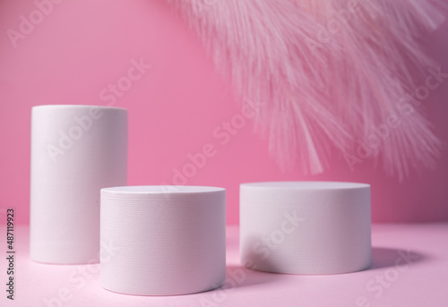 Minimal layout with a podium for product demonstration. Abstract white background of geometric shape on a minimalistic pink background. There are nail polishes on the podium.