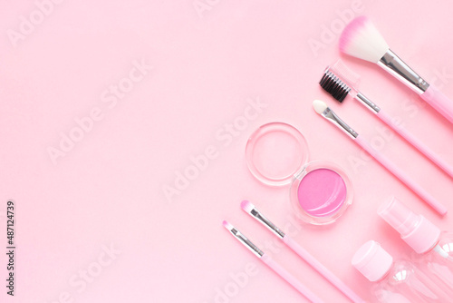 Delicate composition for the beauty sphere: makeup brushes, shadows, cream jars on a pink background. Layout for a beauty blogger or makeup artist. Flat lay, top view