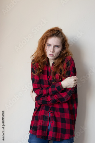 a young girl in a plaid shirt feels bad on a light background