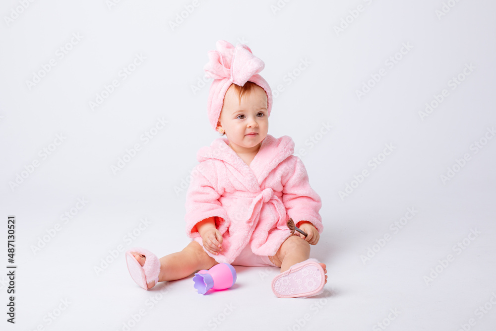 Cute little baby girl in pink terry with makeup isolated on a white background, repeats the behavior of mom Cute little baby girl in pink terry with makeup isolated on a white background, repeats the behavior of mom