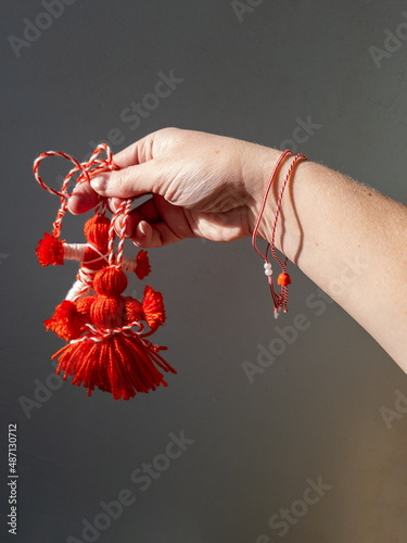 A hand with bracelets holds out a red and white traditional doll, a symbol of the beginning of spring in the Balkan countries. photo