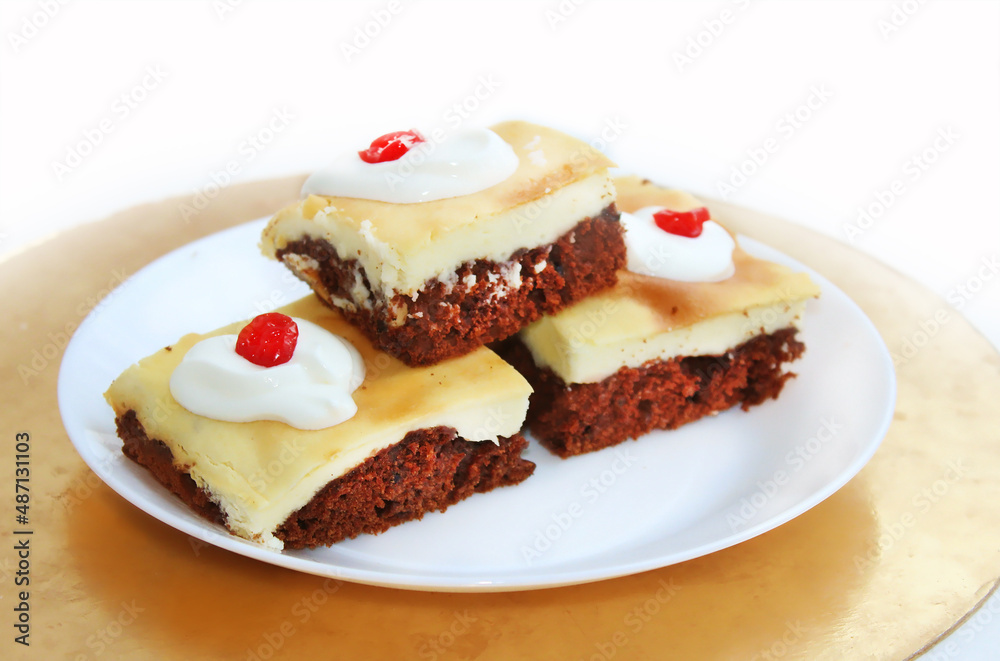 Cheesecake with chocolate biscuit. Pieces of cake on a white plate, sprinkled with sour cream and decorated with dried cherries Cheesecake with chocolate biscuit. Pieces of cake on a white plate, sprinkled with sour cream and decorated with dried cherries