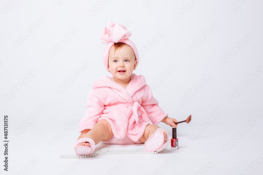 Cute little baby girl in pink terry with makeup isolated on a white background, repeats the behavior of mom Cute little baby girl in pink terry with makeup isolated on a white background, repeats the behavior of mom