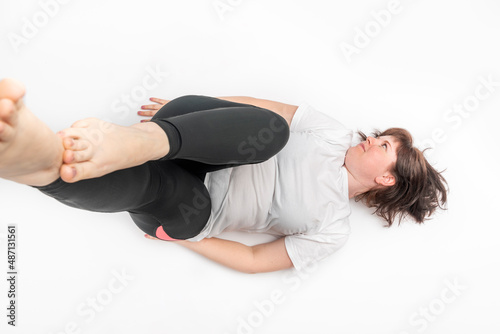 Portrait of a cheerful young girl with a magnificent figure lying on a white background in sportswear.