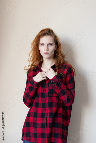 a young girl in a plaid shirt feels bad on a light background