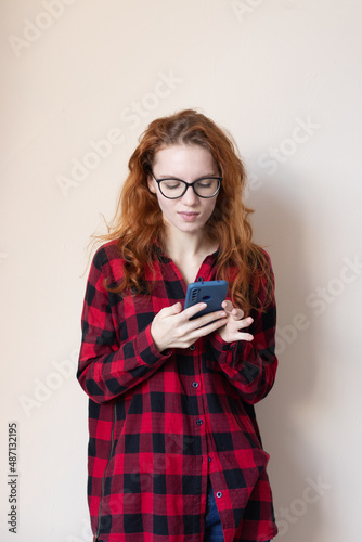young red-haired girl talking on the phone on a light background
