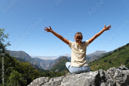 Happy woman celebrating vacation sitting in nature