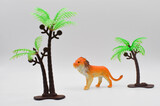 a lion among palm trees.plastic toy on an isolated background.