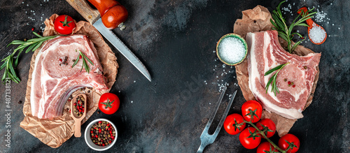 Organic Pork meat chop set with spices and rosemary and red pepper on black table. Long banner format. top view