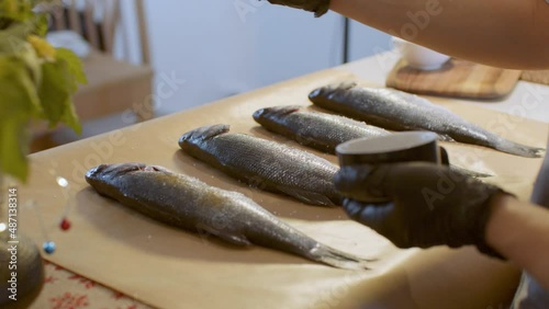 Man’s hands pepper raw fish on the table