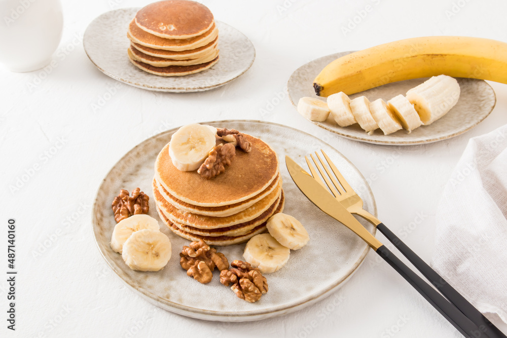 delicious homemade pancakes on a ceramic plate with banana slices and walnuts. a traditional American dessert. delicious homemade pancakes on a ceramic plate with banana slices and walnuts. a traditional American dessert.