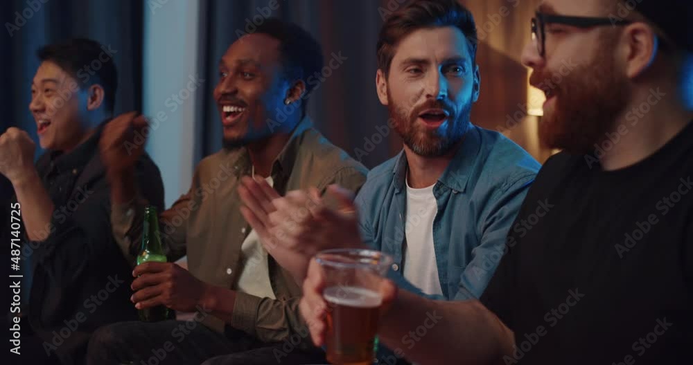 Multinational Men Friends sitting at Home watching Football Cheering. Happy Group of Male Drinking and Resting while looking at TV Having Fun Together. Celebrating Victory. Fans. Quarantine Leisure. Multinational Men Friends sitting at Home watching Football Cheering. Happy Group of Male Drinking and Resting while looking at TV Having Fun Together. Celebrating Victory. Fans. Quarantine Leisure.