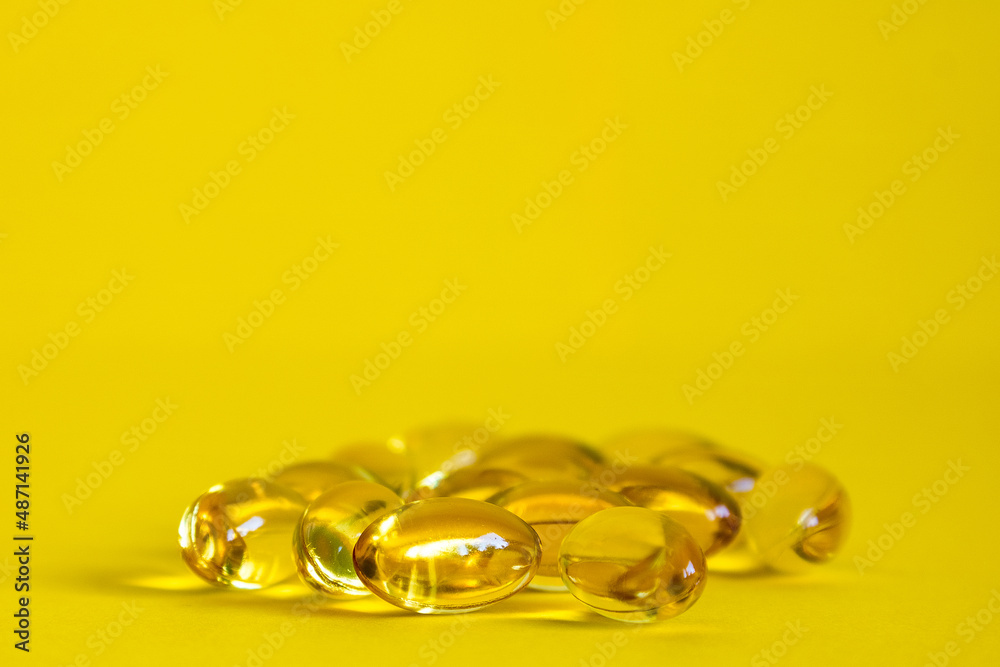 Fish oil capsule, yellow omega 3 capsules, yellow oil tablets on a yellow background Fish oil capsule, yellow omega 3 capsules, yellow oil tablets on a yellow background