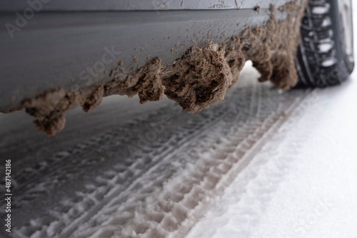 Замерзший грязный снег с солью на пороге и брызговике автомобиля