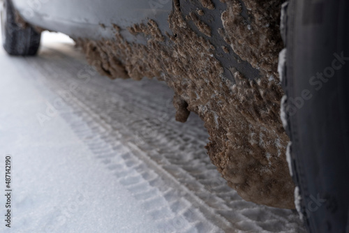 Замерзший грязный снег с солью на пороге и брызговике автомобиля