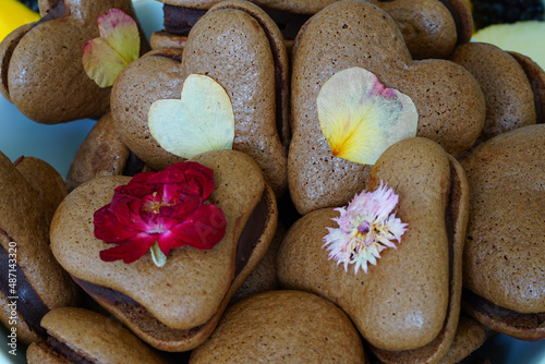 Heart shaped chocolate macaron cookies with pressed edible flowers for Valentines Day
