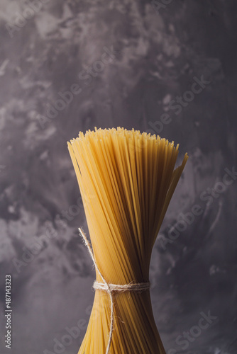 Yellow long raw spaghetti on a gray background. Italian pasta. Food background concept. Beautiful ingredients.