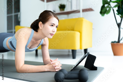 asian Thailand woman exercising doing yoga at home smiling happily Have a strong body good health beautiful skin. using a tablet