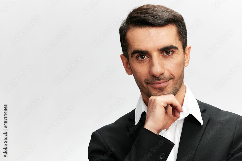 handsome man holding a hand under the chin with a smile posing self-confidence light background handsome man holding a hand under the chin with a smile posing self-confidence light background