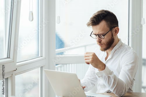 male office worker in business clothes in a white shirt sits at a computer and thinks about a task, the concept of intellectual work.