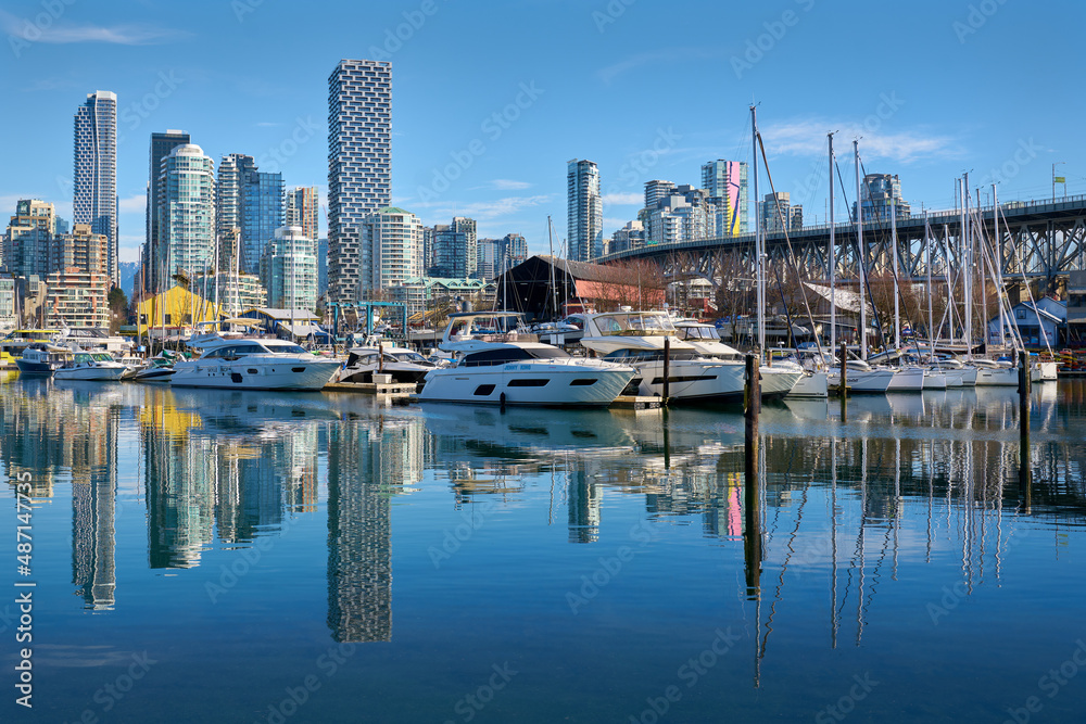 Vancouver, British Columbia, Canada – February 13, 2022. Granville Island Marina Blue Sky Reflections. Yachts in Granville Island Marina on a sunny afternoon. Vancouver, British Columbia, Canada.

