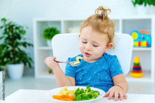 Child baby eats pasta with vegetables. Selective focus.